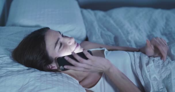 Video Brunett Kvinna Ligger Sängen Och Prata Smartphone — Stockvideo
