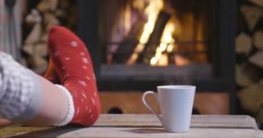 Soğuk sonbahar ya da kış akşam. İnsanlar ateşin yanında battaniye ve çay ile dinlenme. Yün çorap ayaklarda closeup fotoğraf. Sıcak sahne.