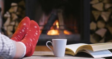 Soğuk sonbahar ya da kış akşam. İnsanlar ateşin yanında battaniye ve çay ile dinlenme. Yün çorap ayaklarda closeup fotoğraf. Sıcak sahne.