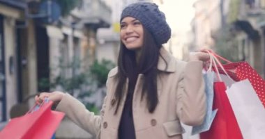 ağır çekim video renkli alışveriş torbaları ile şehirde yürüyüş şapkalı güzel esmer kadının