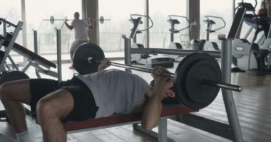 Salondaki, gömleksiz adam vücudu fit kalmak ve kasları tanımlamış olduğunuz için eğitiyor. Atlet ağır ağırlık ve yorgunluk yükseltir. Kavramı: spor, spor salonu, kas ve fitness