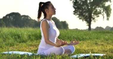 Açık havada yeşil çim çayır, meditasyon poz yoga yapıyor kadın video