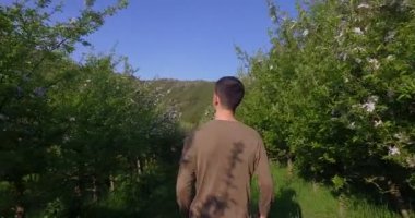 Genç bir çiftçi (çiftlik) güzel bir bahçe ağaçları ile sunset Bulvarında yürürken görünümünü. Konsept: biyo, çiftlik, doğa