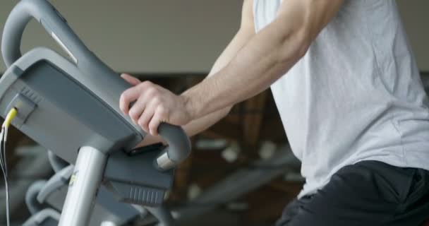 视频英俊的高加索肌肉男在健身房锻炼固定自行车 — 图库视频影像