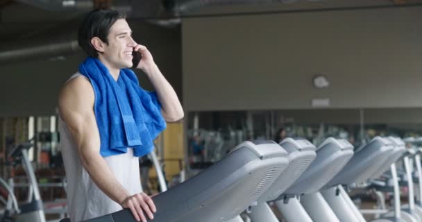 在跑步机上用蓝色毛巾在肩膀上和会说话的手机的高加索人慢动作视频 — 图库视频影像