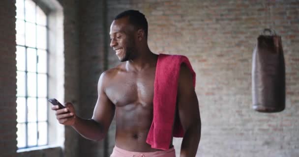 スマート フォンを使用して上半身裸の笑みを浮かべてアフリカ男のビデオ — ストック動画