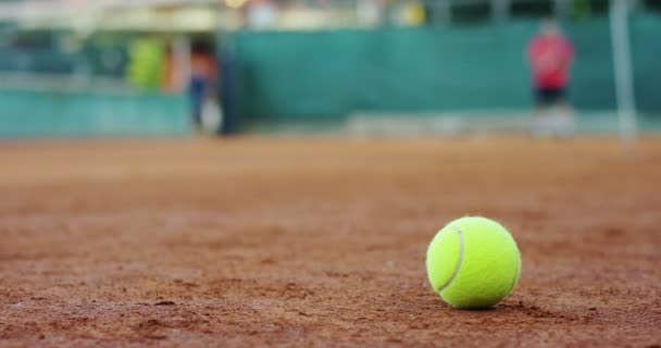 プロのテニス ラケットとテニス プレーヤーのデフォーカス赤土バック グラウンドでフィールドのスローモーション — ストック動画