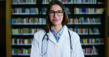 Genç ve güzel kadın doktor mutlu ve tutan kitaplar bir arama yaptıktan sonra ve sonra eğitim gülümseyen bir Kitaplığı'nda. Konsept: eğitim, portre, Kütüphane ve tıbbi bakım ve refah