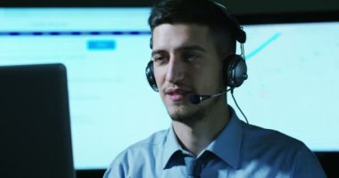 Müşteri Hizmetleri veya bazı Havaalanı kontrol kulesi istasyonunda çalışan genç bir adam, bir gülümseme müşterilere telefon aramaları ve gündüz cevaplar.
