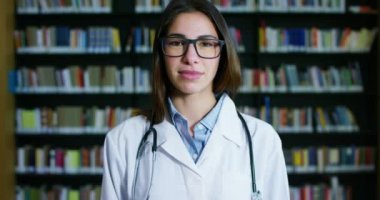 Genç ve güzel kadın doktor mutlu ve tutan kitaplar bir arama yaptıktan sonra ve sonra eğitim gülümseyen bir Kitaplığı'nda. Konsept: eğitim, portre, Kütüphane ve tıbbi bakım ve refah