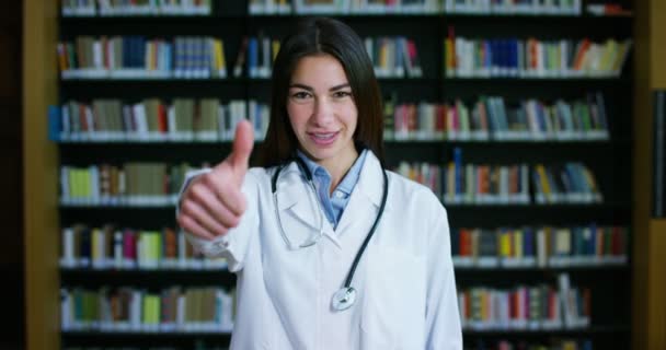 Una Joven Hermosa Doctora Una Biblioteca Sonriendo Feliz Sosteniendo Libros — Vídeos de Stock