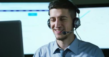 Müşteri Hizmetleri veya bazı Havaalanı kontrol kulesi istasyonunda çalışan genç bir adam, bir gülümseme müşterilere telefon aramaları ve gündüz cevaplar.