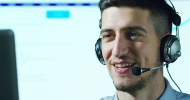 Müşteri Hizmetleri veya bazı Havaalanı kontrol kulesi istasyonunda çalışan genç bir adam, bir gülümseme müşterilere telefon aramaları ve gündüz cevaplar.