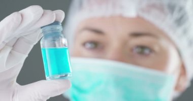 mavi sıvı ile küçük cam tüp tutan tıp maskesi bilim adamı kadın video 