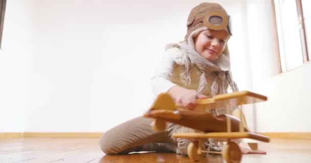 Speelse Schattig Meisje Gekleed Als Pilot Zittend Een Houten Vloer — Stockvideo