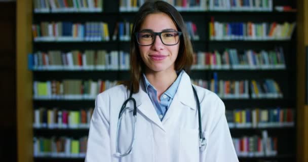 Una Joven Hermosa Doctora Una Biblioteca Sonriendo Feliz Sosteniendo Libros — Vídeos de Stock