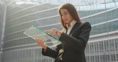 kullanarak ve şeffaf dijital tablet tarama ve bina, office cam dünya gezegen hologram ayakta işkadını ağır çekim video 