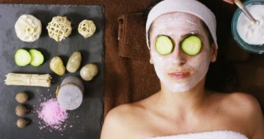 Yüz maskesi ve salatalık tedavisi yüzünde genç kadın portresi bir relax bir Sağlık Merkezi var. Cilt Bakımı, kozmetik, güzellik salonları, yüz tedavisi, yüz masajı, refah kavramı