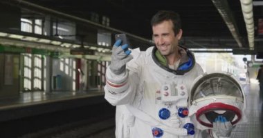 Bir astronot giymiş adam akıllı telefon çağrı ve mesaj göndermek için kullanır. Elinde telefon bakarak süre astronot gülümsüyor. Kavramı: telefon promosyonlar, iletileri ve uzaysal aramalar.