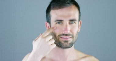 Çok yakışıklı bir adam gülümsüyor ve anti-kırışıklık ve anti-aging vücut bakımı için yüz kremi ve göz kontur koyar ve güzellik bilir. Konsept: Güzellik, krem, güzellik