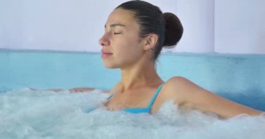 Güzel genç kız (kadın) bir mavi mayo içinde mavi bir arka plan üzerinde bir hidromasaj küveti rahat. Konsept: spa prosedürler, vücut masajları, spa krem, sakin ol, spa su tedavileri, yüzme havuzu