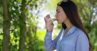 Güzel genç kız bir cam holding ve doğa arka planında doğal olarak temiz su, içme. Konsept: ekoloji, saflık, diyet, doğal saf kaynaklardan, çevre, canlandırıcı, sağlıklı.