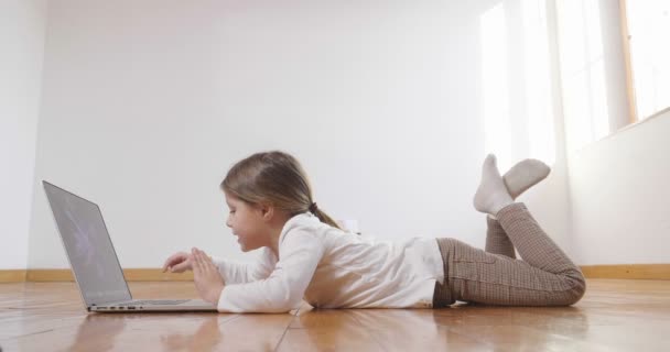 床の上に横たわると ラップトップ コンピューターを使用して小さな女の子 — ストック動画