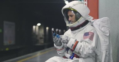 Bir astronot giymiş adam akıllı telefon çağrı ve mesaj göndermek için kullanır. Elinde telefon bakarak süre astronot gülümsüyor. Kavramı: telefon promosyonlar, iletileri ve uzaysal aramalar.