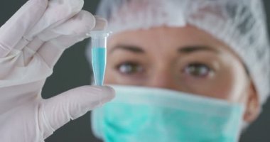 mavi sıvı ile küçük cam tüp tutan tıp maskesi doktor kadın video 