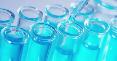Bir laboratuarda, pipetli bir bilim adamı test tüplerindeki DNA ve molekülleri ayırmak için renkli bir sıvıyı analiz eder. Konsept: araştırma, biyokimya, doğa, ilaç