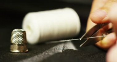 Onun Studio elbise dikmek için terzi araçları ile dikmek için iş parçacığı kesen genç bir terzi elin ağır çekim