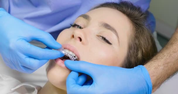 女性の歯から取り外し可能な Invisalign トレイを取る医師のビデオ — ストック動画