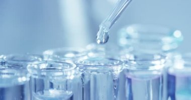 Bir laboratuarda, pipetli bir bilim adamı test tüplerindeki DNA ve molekülleri ayırmak için renkli bir sıvıyı analiz eder. Konsept: araştırma, biyokimya, doğa, ilaç