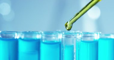 Bir laboratuarda, pipetli bir bilim adamı test tüplerindeki DNA ve molekülleri ayırmak için renkli bir sıvıyı analiz eder. Konsept: araştırma, biyokimya, doğa, ilaç