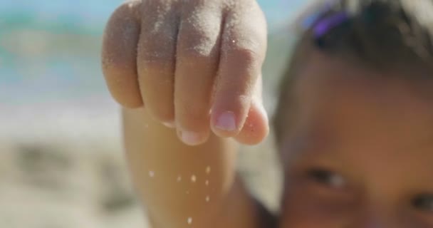 小さな女の子が遊んで海 小さな足 水着で砂海の背景黄色の砂と青い水 コンセプト 子供のころ — ストック動画
