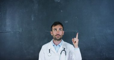 Beyaz laboratuar ceket giyen profesyonel doktor adam video ve stetoskop parmak yukarı işaret 