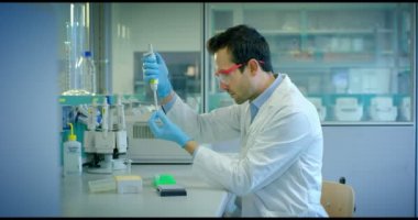 güzel genç bilim adamı erkek doktor sıvı virüs hücreleri kullanarak nitelikli ekipman ve gözleri korumak için gözlük takan ve laboratuvar bardak bakımı profesyonel Laboratuvar analiz