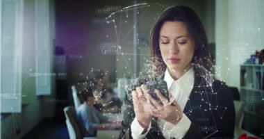 hologram ile cep telefonu tutan iş kadını video, arka planda ofiste masada oturan meslektaşları 