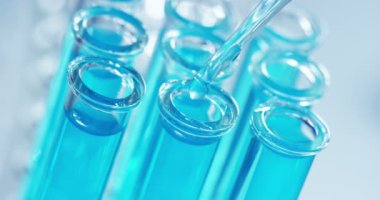 Bir laboratuarda, pipetli bir bilim adamı test tüplerindeki DNA ve molekülleri ayırmak için renkli bir sıvıyı analiz eder. Konsept: araştırma, biyokimya, doğa, ilaç