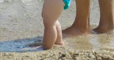 Bir anne ilk adımları küçük bebeği sahilde adım adım yapar tatile yenidoğan yürümeyi öğrenir...