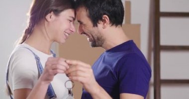 Portre aşık bir çiftin yere oturmuş ve onlar sadece bir ev satın aldı ve hareket ediyor. Gelin ve damat gülümse ve ellerinde yeni ev tuşlarını basılı tutun. Kavramı: gelecek, Aile.