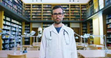 Kitaplığa bir arama yaptıktan sonra ve eğitim sonra mutlu ve tutan kitaplar gülümseyen genç ve güzel bir doktor. Konsept: eğitim, portre, Kütüphane ve tıbbi bakım ve refah