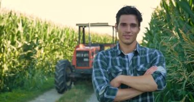Alanında başarılı bir traktör ile çalışma güzel genç bir çiftçi (öğrenci) portresi gülümseyen, mutlu bir gömlek, Mısır alan. Kavram ekoloji, taşıma, çiftçiler, temiz hava, yiyecek, bio ürün