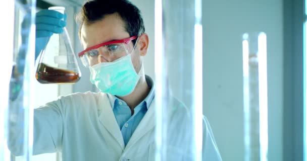 素敵な若手男性医師限定設備および目を保護する眼鏡およびラボ メガネの世話を使用してプロの研究室で液体ウイルス細胞を解析 — ストック動画