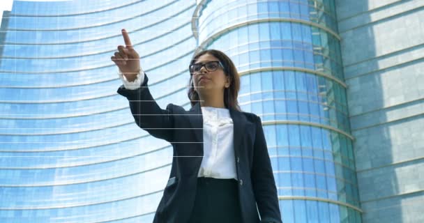 女商人在西装触摸全息图财务图表的视频 现代玻璃建筑的背景 — 图库视频影像