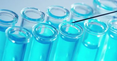 Bir laboratuarda, pipetli bir bilim adamı test tüplerindeki DNA ve molekülleri ayırmak için renkli bir sıvıyı analiz eder. Konsept: araştırma, biyokimya, doğa, ilaç