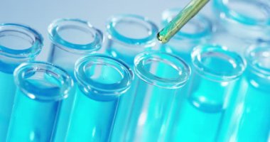 Bir laboratuarda, pipetli bir bilim adamı test tüplerindeki DNA ve molekülleri ayırmak için renkli bir sıvıyı analiz eder. Konsept: araştırma, biyokimya, doğa, ilaç