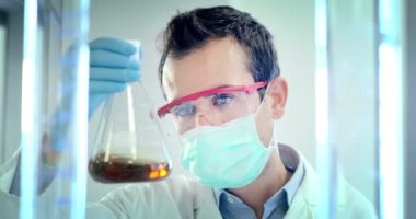 güzel genç bilim adamı erkek doktor sıvı virüs hücreleri kullanarak nitelikli ekipman ve gözleri korumak için gözlük takan ve laboratuvar bardak bakımı profesyonel Laboratuvar analiz