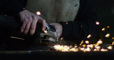 Demirci ya da kaynakçı, çelik ve demiri son derece yavaş çekimde yüzeyi pürüzsüz hale getirmek için öğütüyor. Demirle değirmen tekerleği teması kıvılcımlara neden oluyor. İş, çilingir endüstrisi, çilingir endüstrisi..