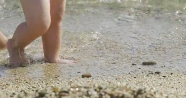 Bir anne ilk adımları küçük bebeği sahilde adım adım yapar tatile yenidoğan yürümeyi öğrenir...